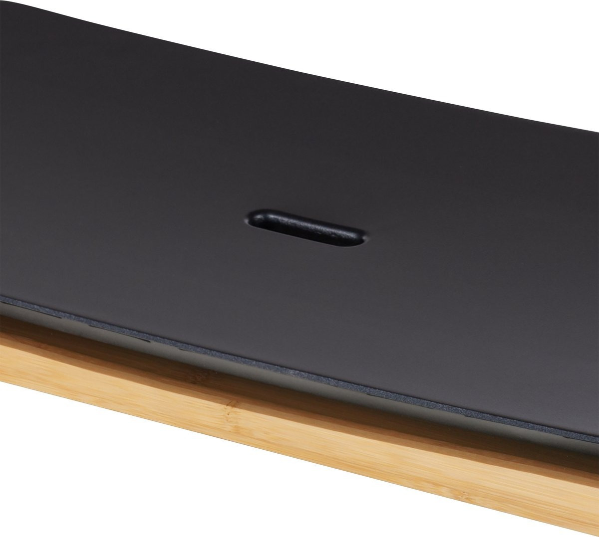 A black surface with a single, oval-shaped indentation. The surface is set upon a bamboo base.