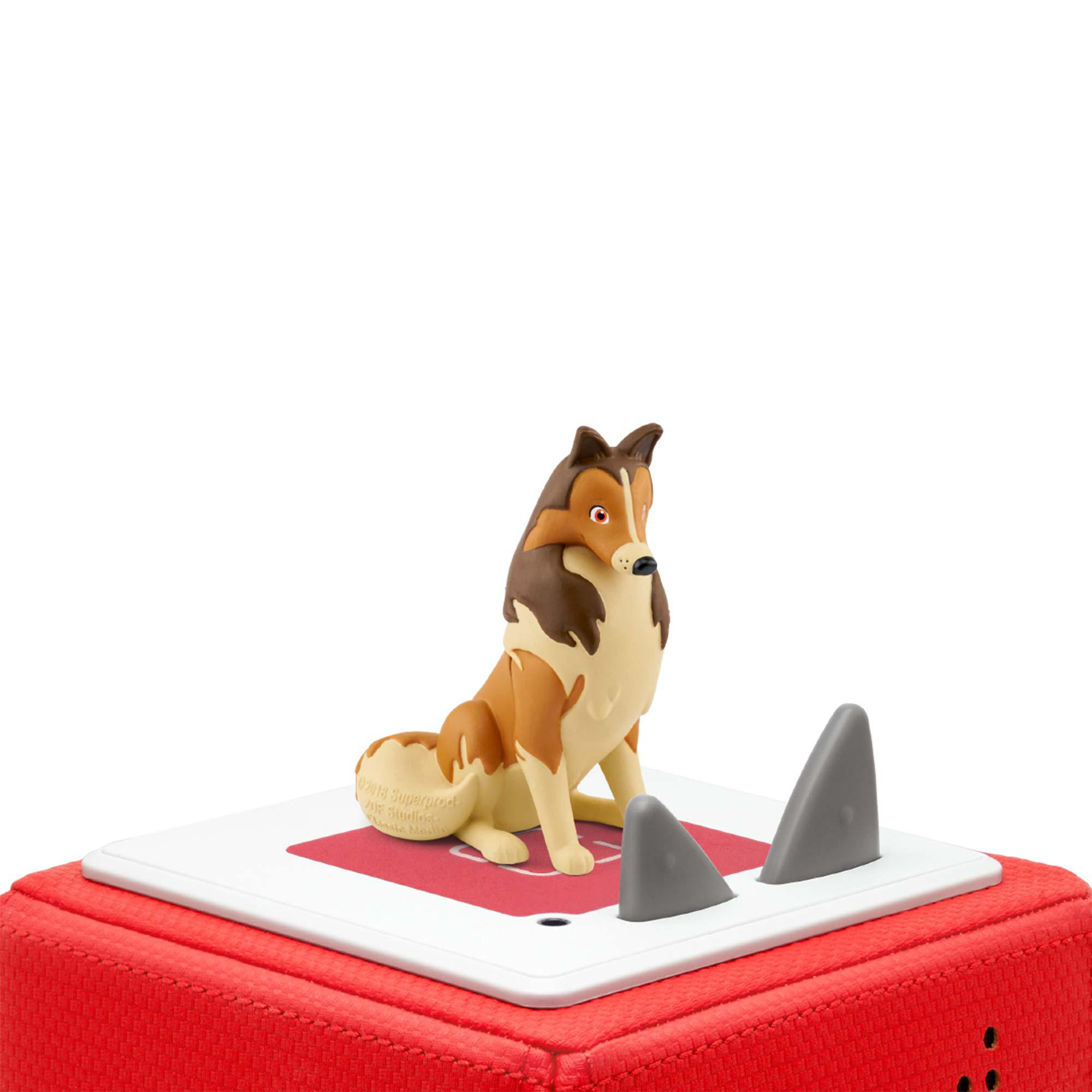 Eine Hundespielzeugfigur eines Collies, die auf einer rot-weißen Plattform sitzt, mit zwei grauen, haifischflossenartigen Objekten.