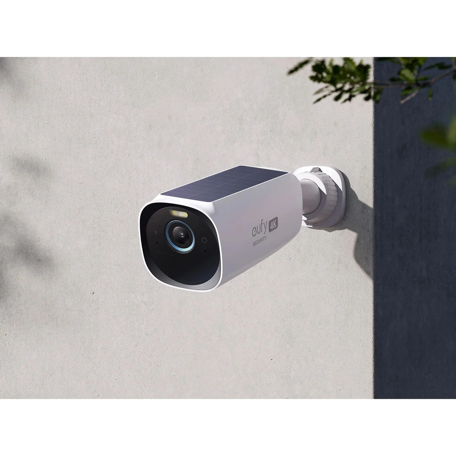 A white security camera mounted on a wall. It has a solar panel on top and a black lens.