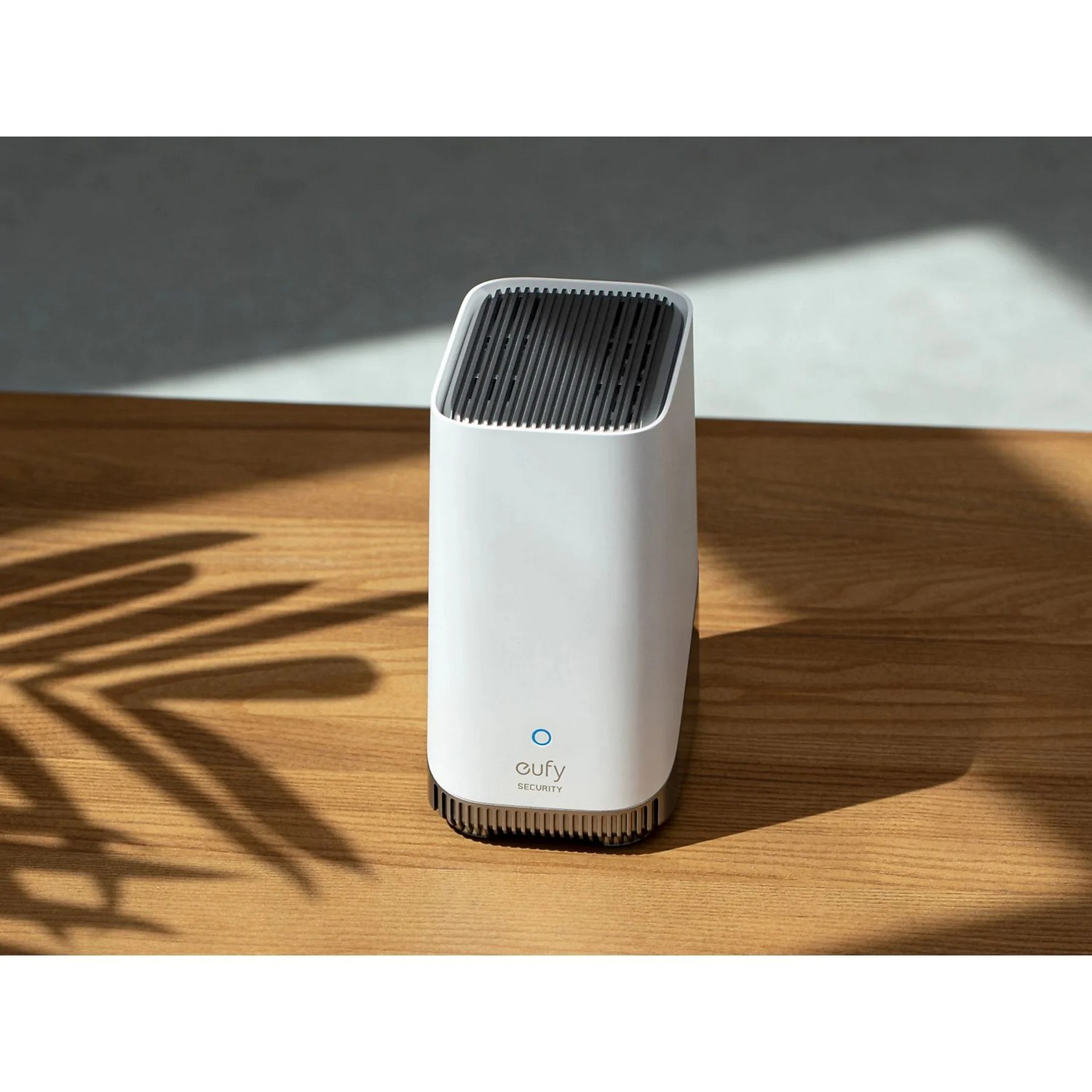 White eufy security device on a wooden table. A shadow is cast.