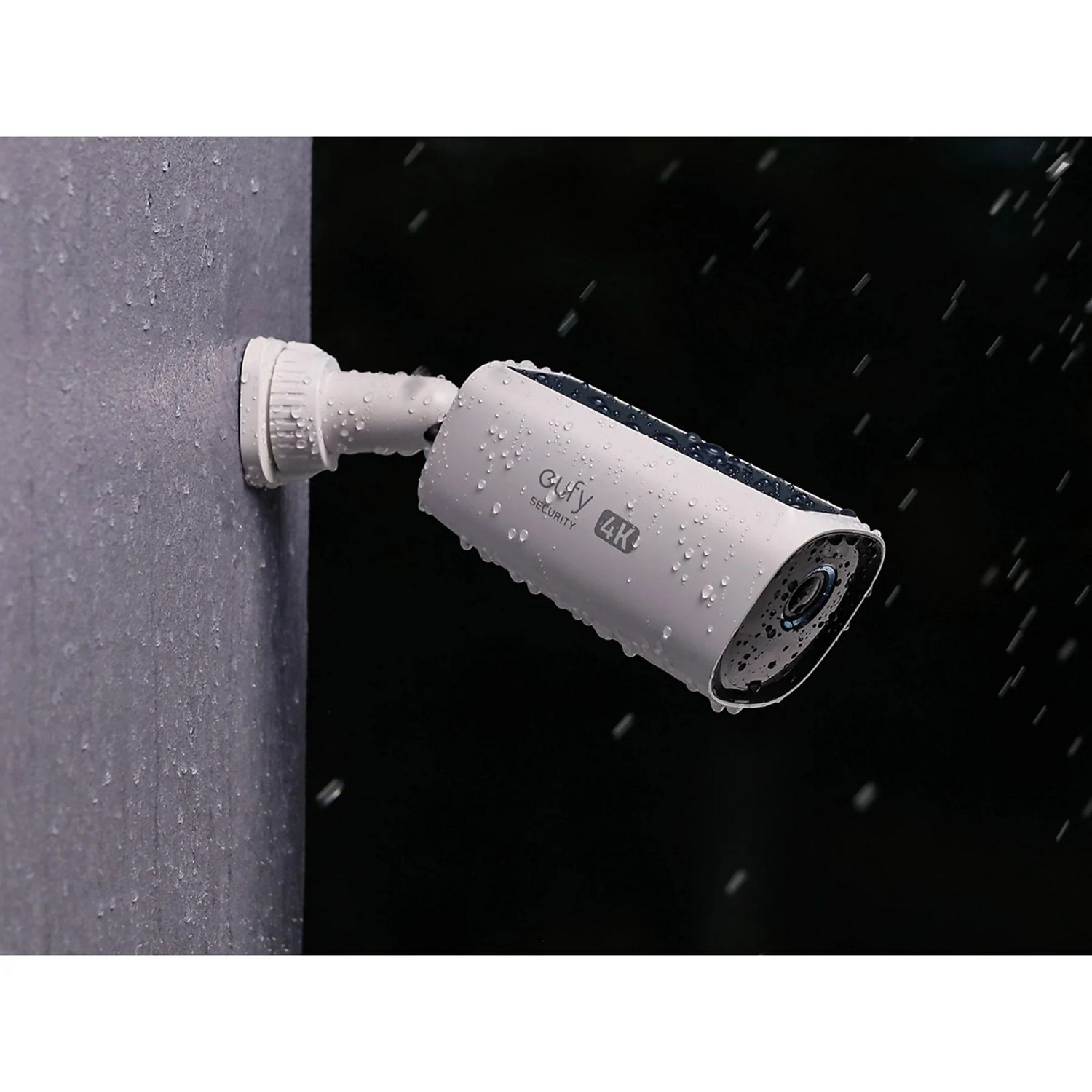 White security camera mounted on a wall, with water droplets. The lens is black.