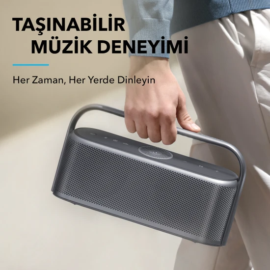 Taşınabilir gri bir hoparlör tutan kişi. Türkçe metin: 'Taşınabilir Müzik Deneyimi'.