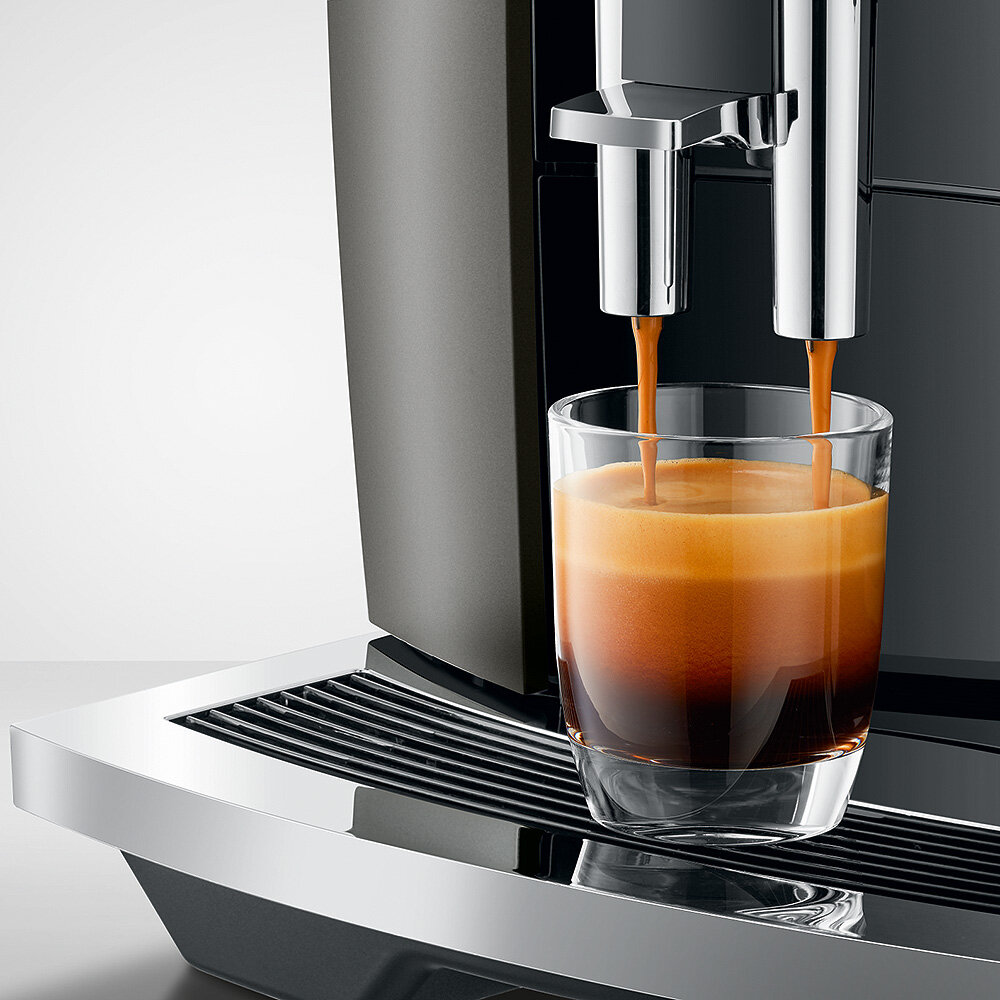 Ekspres do kawy nalewający kawę do szklanki. Kawa ma warstwy.