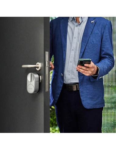 Un hombre con una chaqueta azul abre una puerta con una cerradura inteligente. La puerta es plateada.