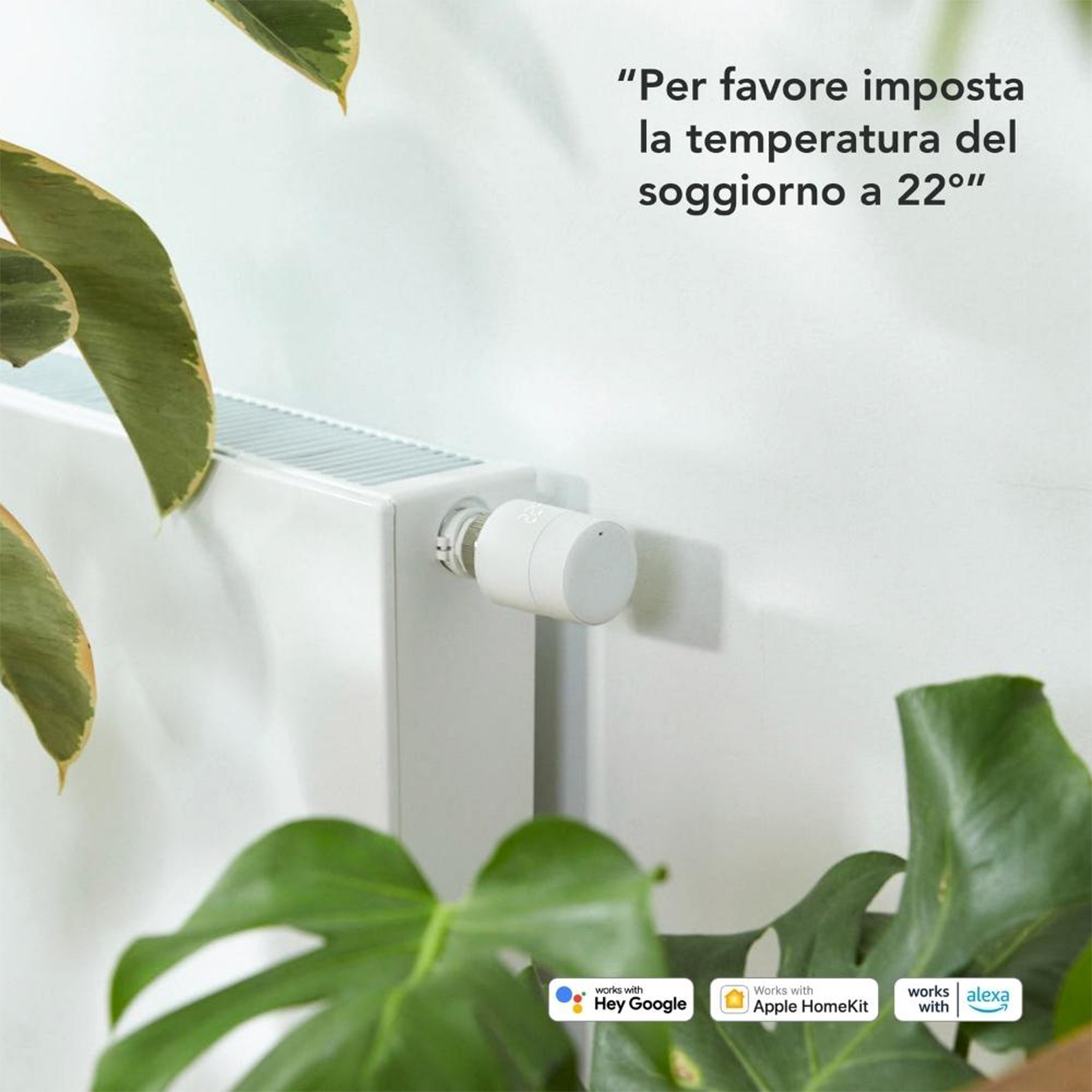 Un radiatore bianco con un termostato intelligente. Foglie verdi e un muro bianco sullo sfondo.