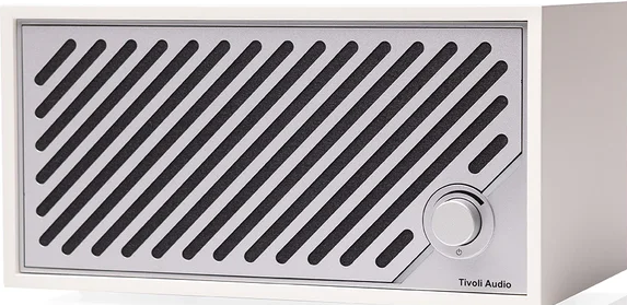Une radio Tivoli Audio blanche. Elle possède une grille de haut-parleur avec des lignes noires diagonales, un bouton argenté et le nom de la marque.
