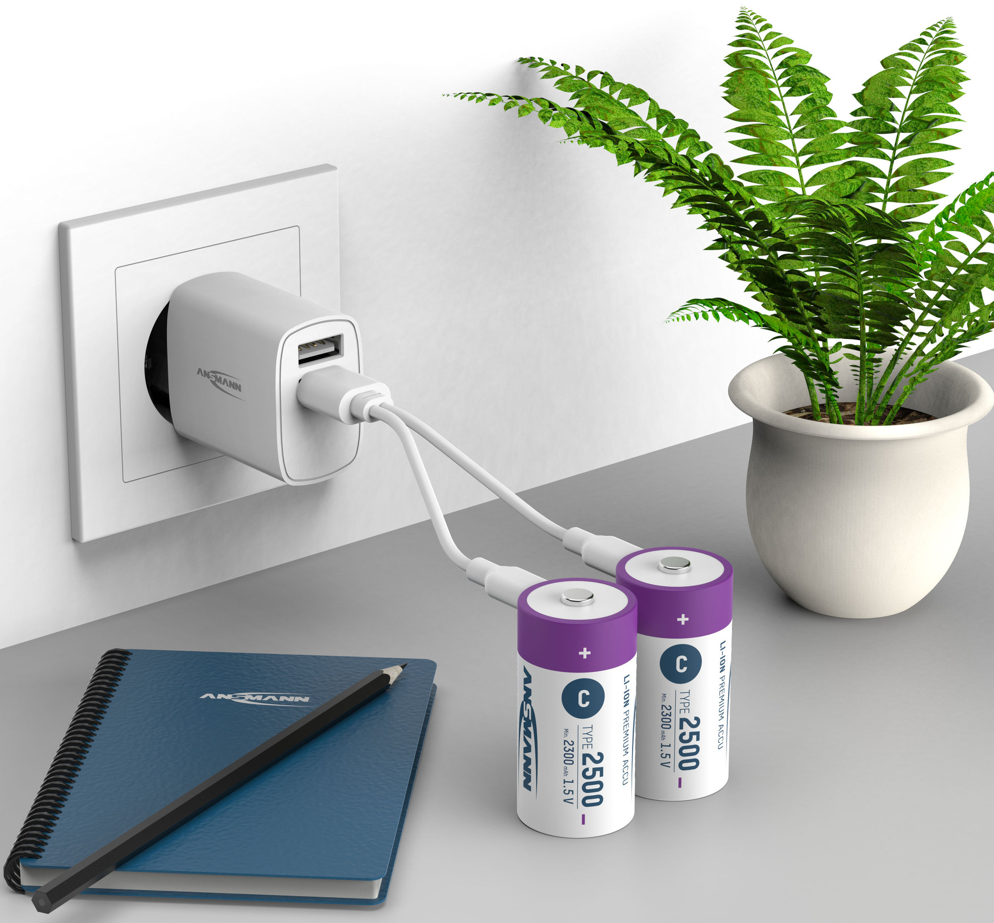 Chargeur blanc branché au mur, chargeant deux piles violettes. Un cahier bleu et un crayon sont présents.
