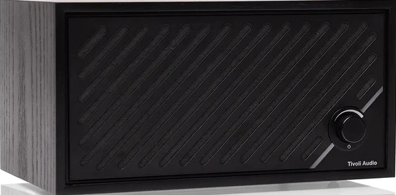 Haut-parleur noir avec bouton de volume et logo Tivoli Audio. Le haut-parleur a des lignes diagonales et des côtés en bois.