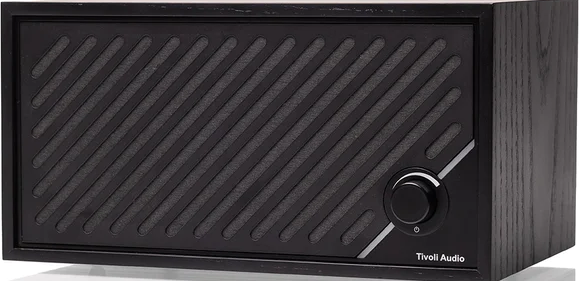 Un haut-parleur Tivoli Audio noir. Il a un cache-haut-parleur à lignes diagonales, un bouton et un boîtier en bois.