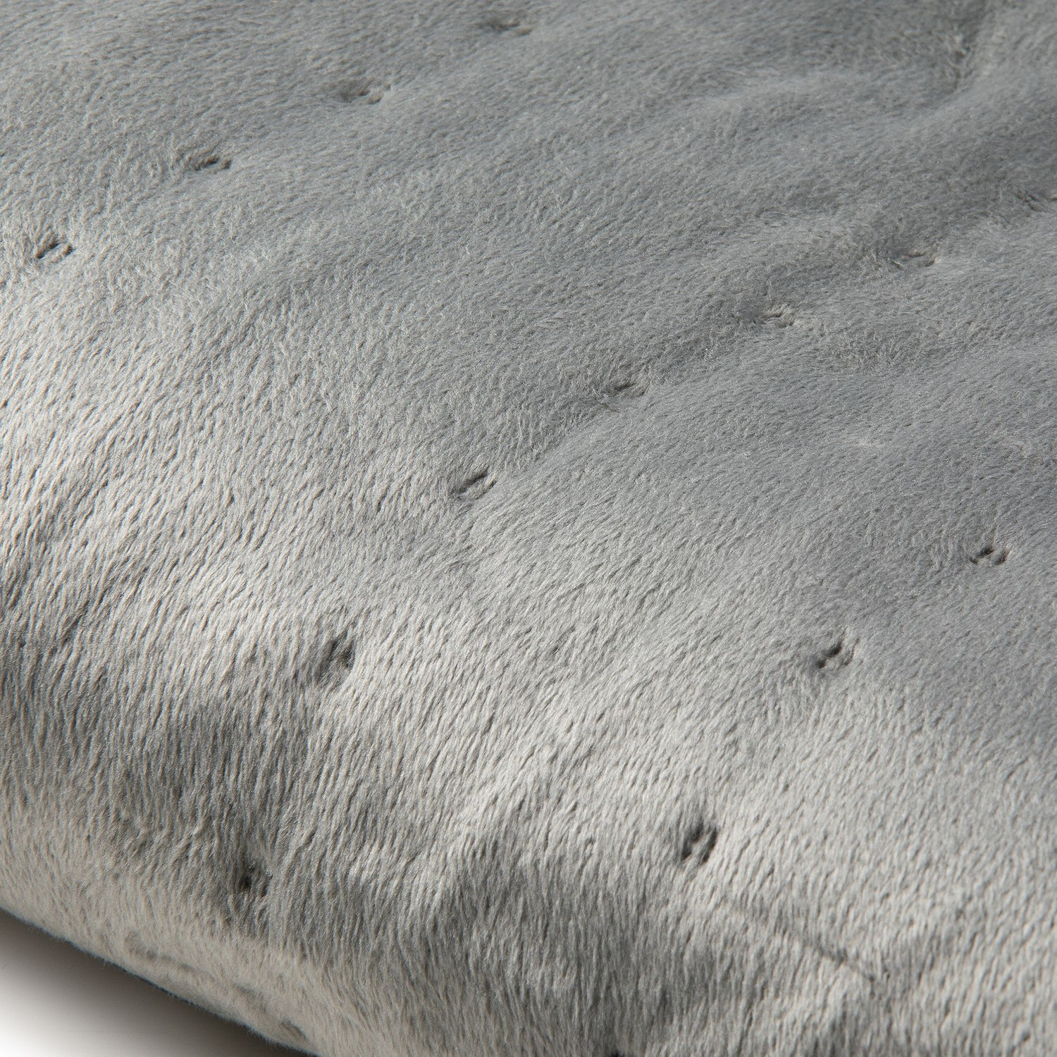 Gros plan sur une surface douce, grise et matelassée. La texture est moelleuse avec de petits points creux.