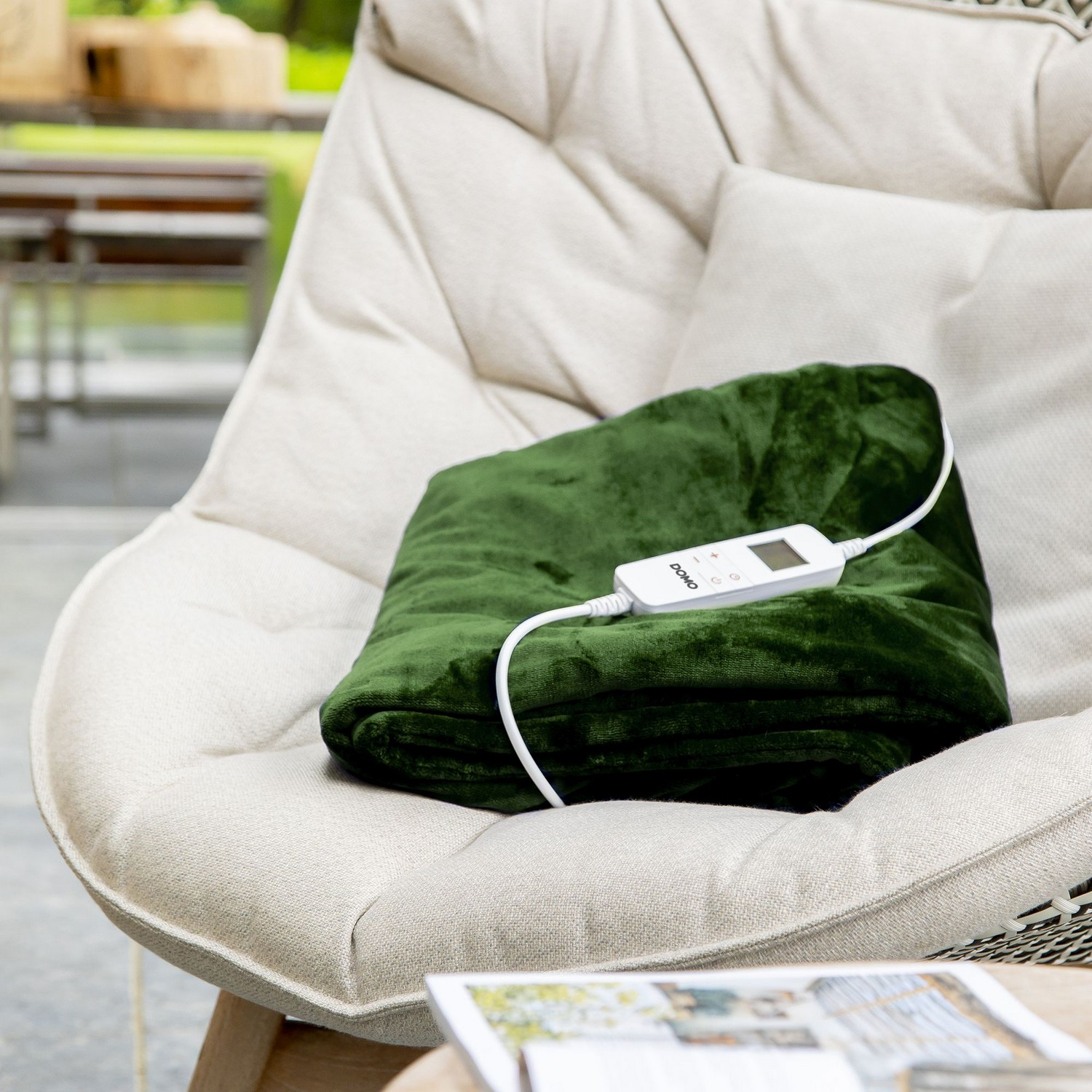 Couverture chauffante verte sur chaise. Panneau de commande blanc attaché. Extérieur.