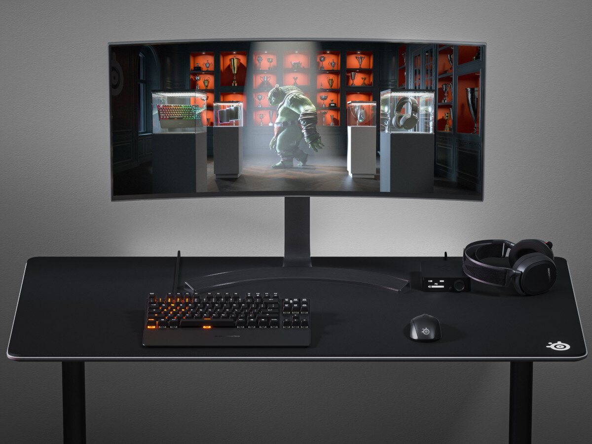 Konfiguracja do gier z zakrzywionym monitorem, klawiaturą, myszą i słuchawkami. Na ekranie wyświetlana jest postać.