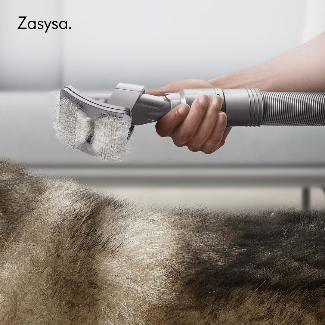 Ręka trzyma narzędzie do pielęgnacji zwierząt, odkurzając sierść psa.