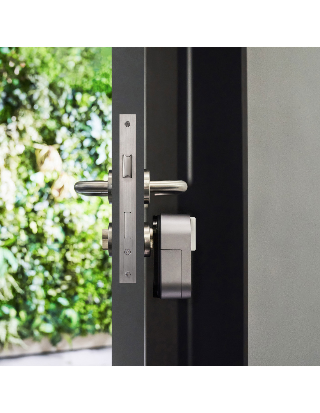 Puerta con manija de metal cepillado y sistema de cerradura inteligente, sobre fondo verde.
