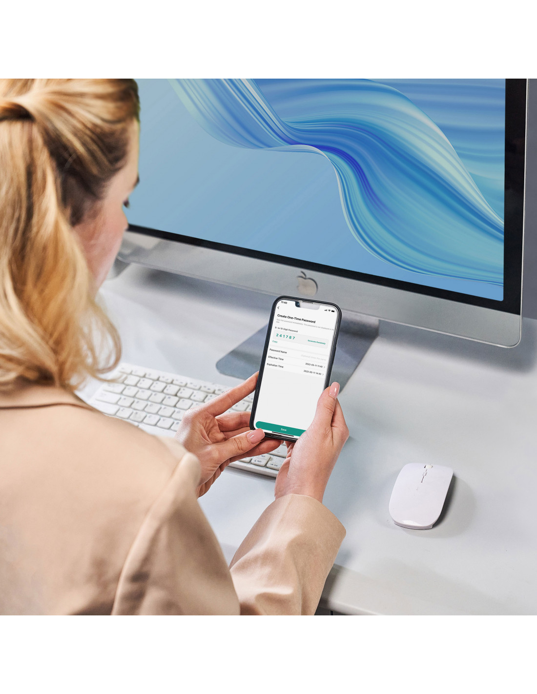 Una mujer usando un teléfono en un escritorio. Un monitor y un ratón están en el fondo.