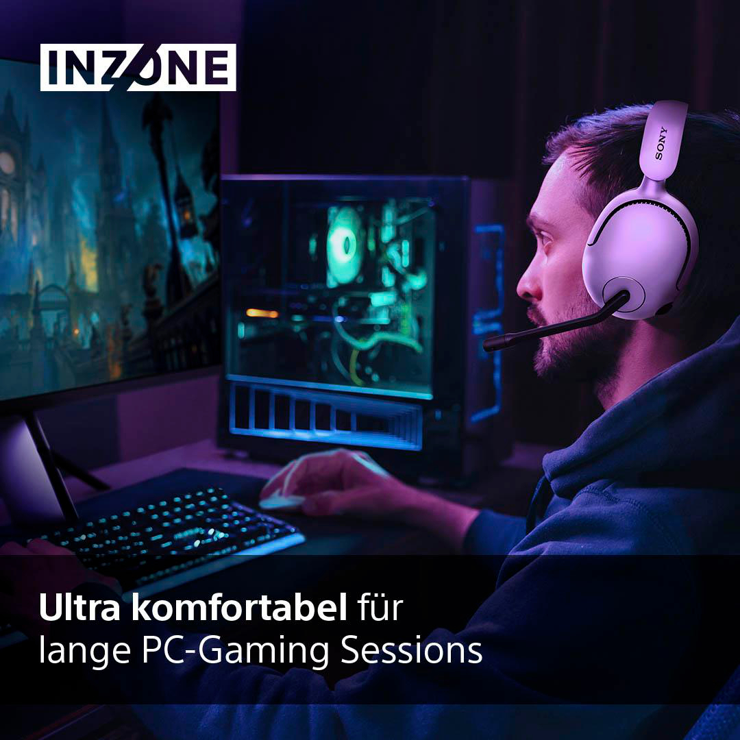 Ein Mann mit Kopfhörern, der in einem dunklen Raum mit Neonlichtern am Computer spielt.