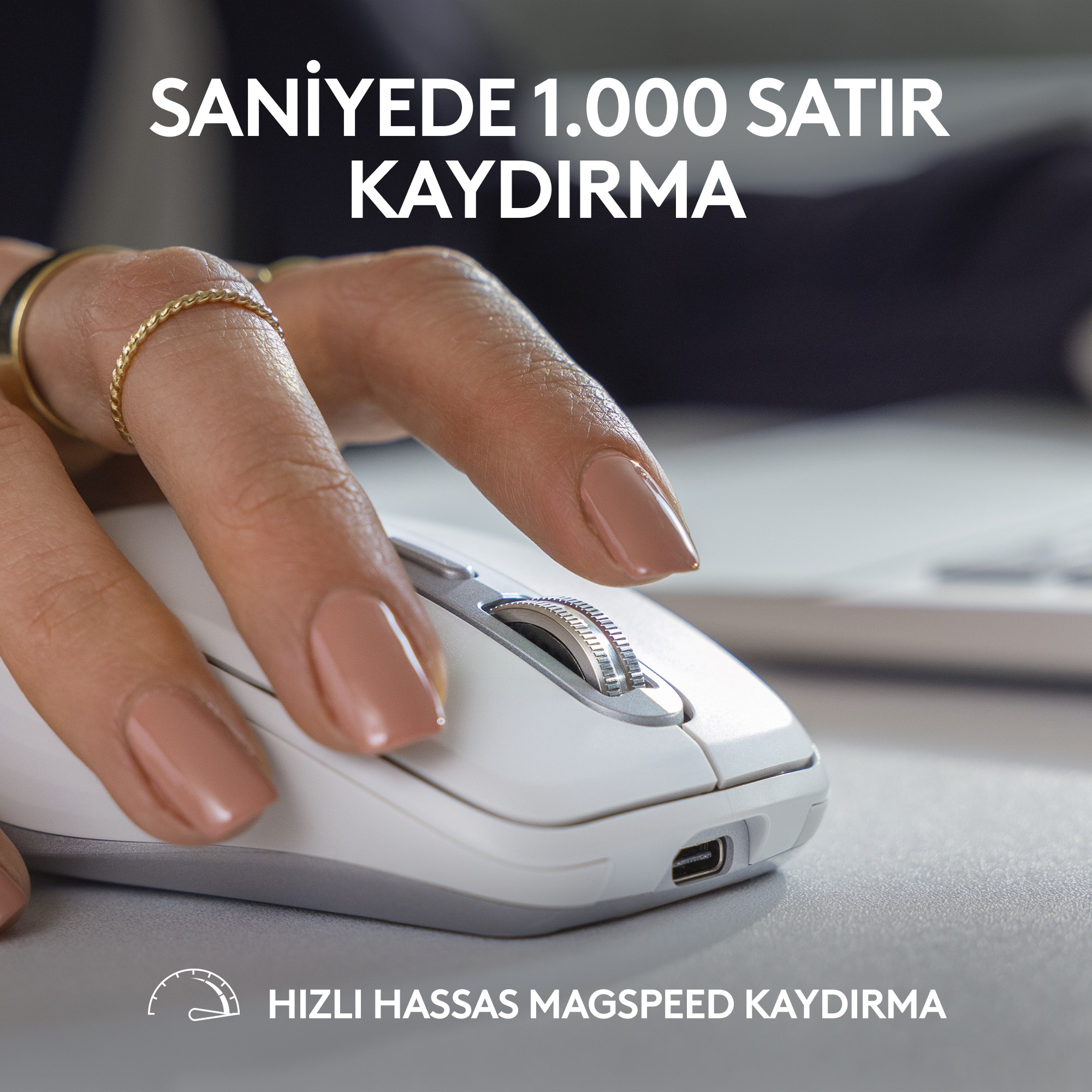 Beyaz bir fare kullanan bir elin yakın çekimi. Farenin bir kaydırma tekerleği ve bir şarj bağlantı noktası var.