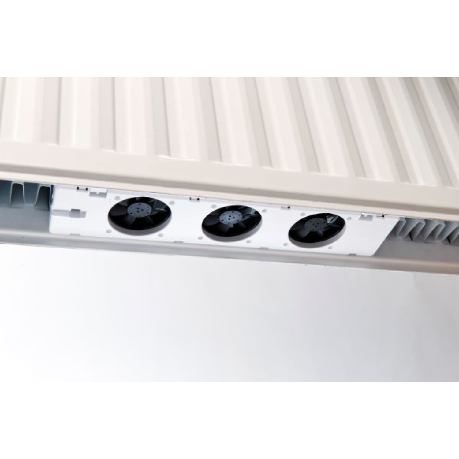 Close up of three black fans inside a white ventilation system, seen from below, on a white background.