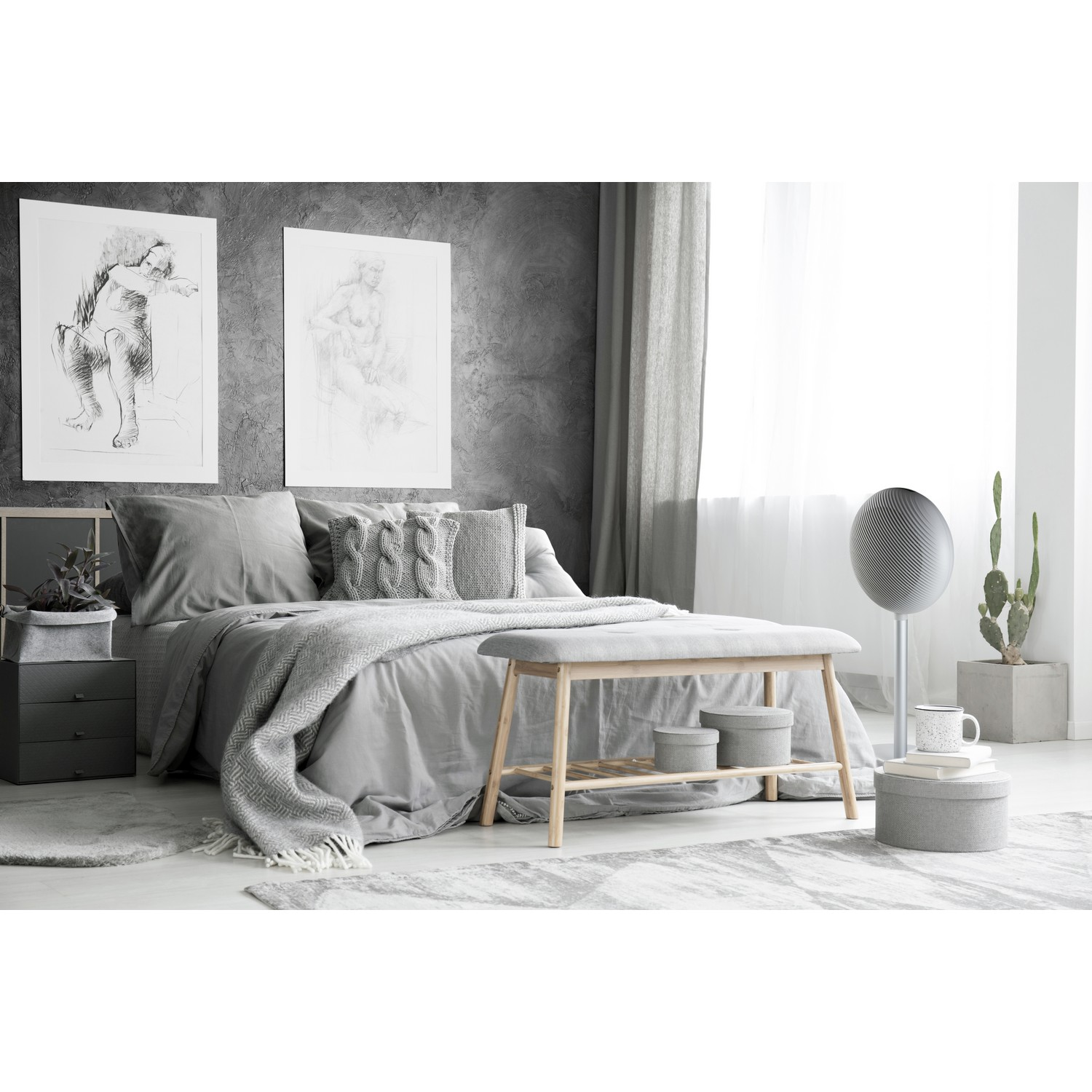Bedroom with gray decor. Bed, bench, and artwork are visible. A cactus and a speaker are also shown.
