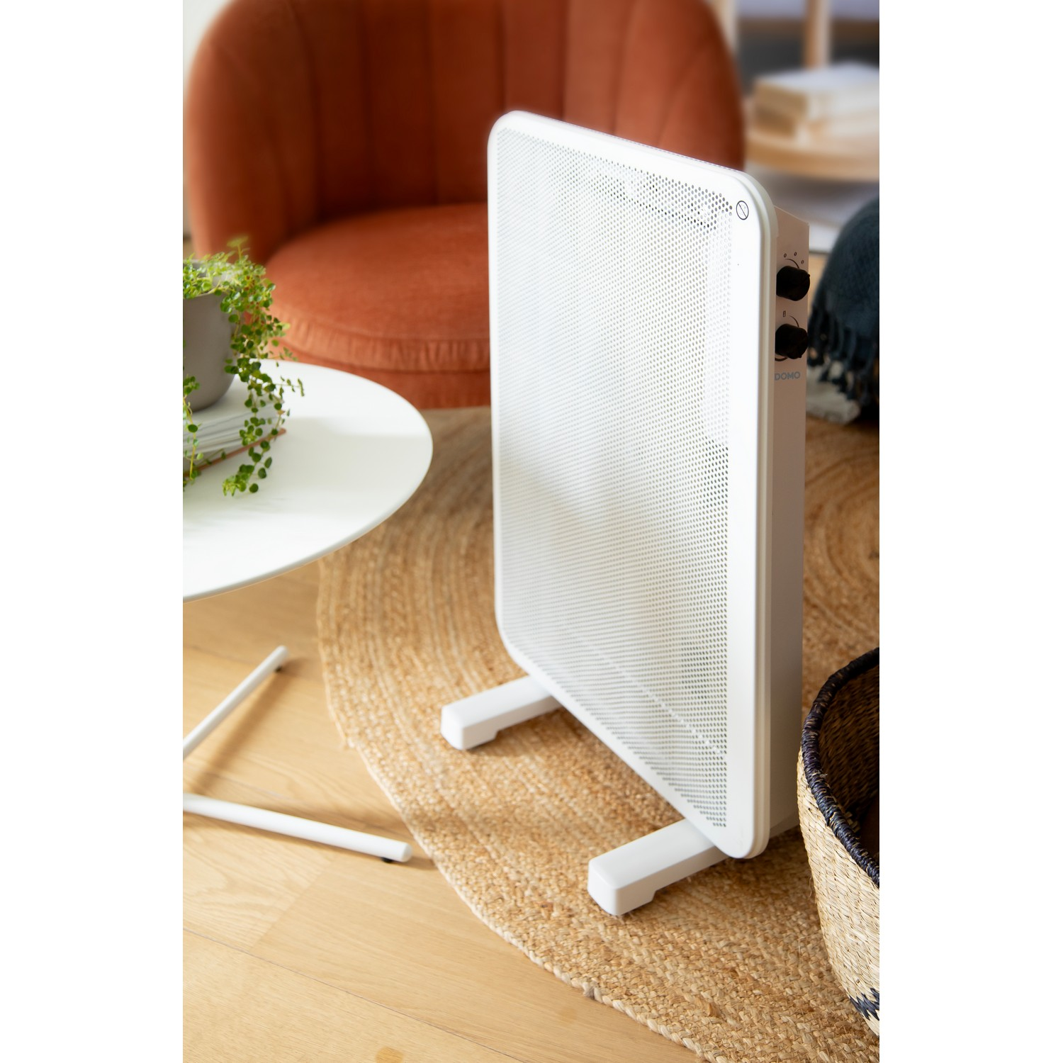White electric heater on a rug, with a white table and an orange chair in the background.