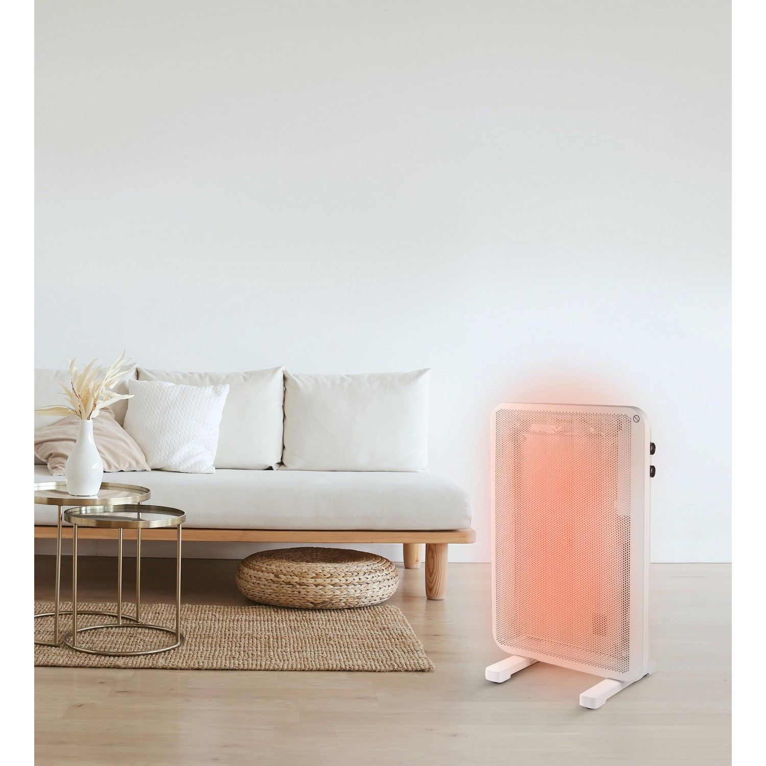 A white electric heater is in a living room, next to a couch and table. The heater glows orange.
