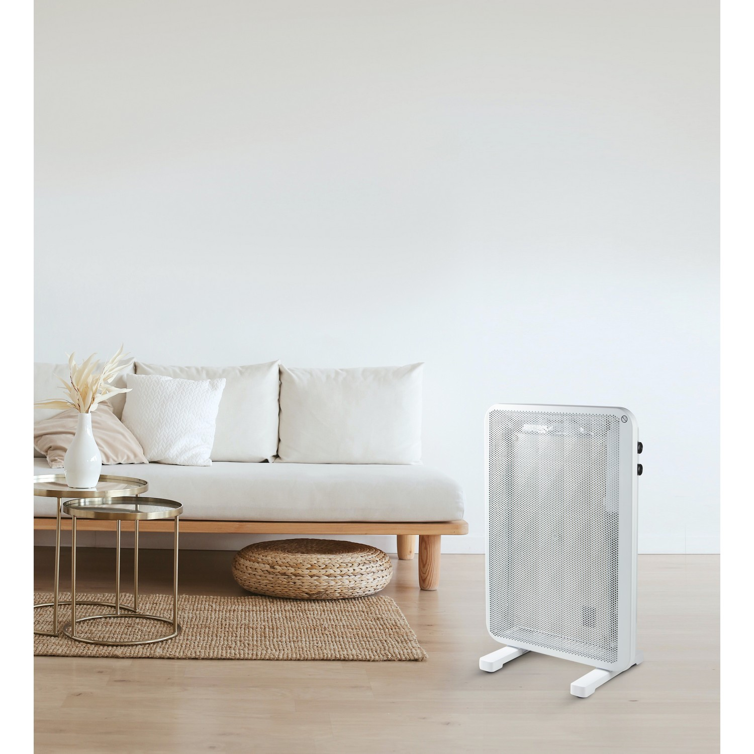 A white electric heater stands in a living room. A sofa, table, and rug are also present.
