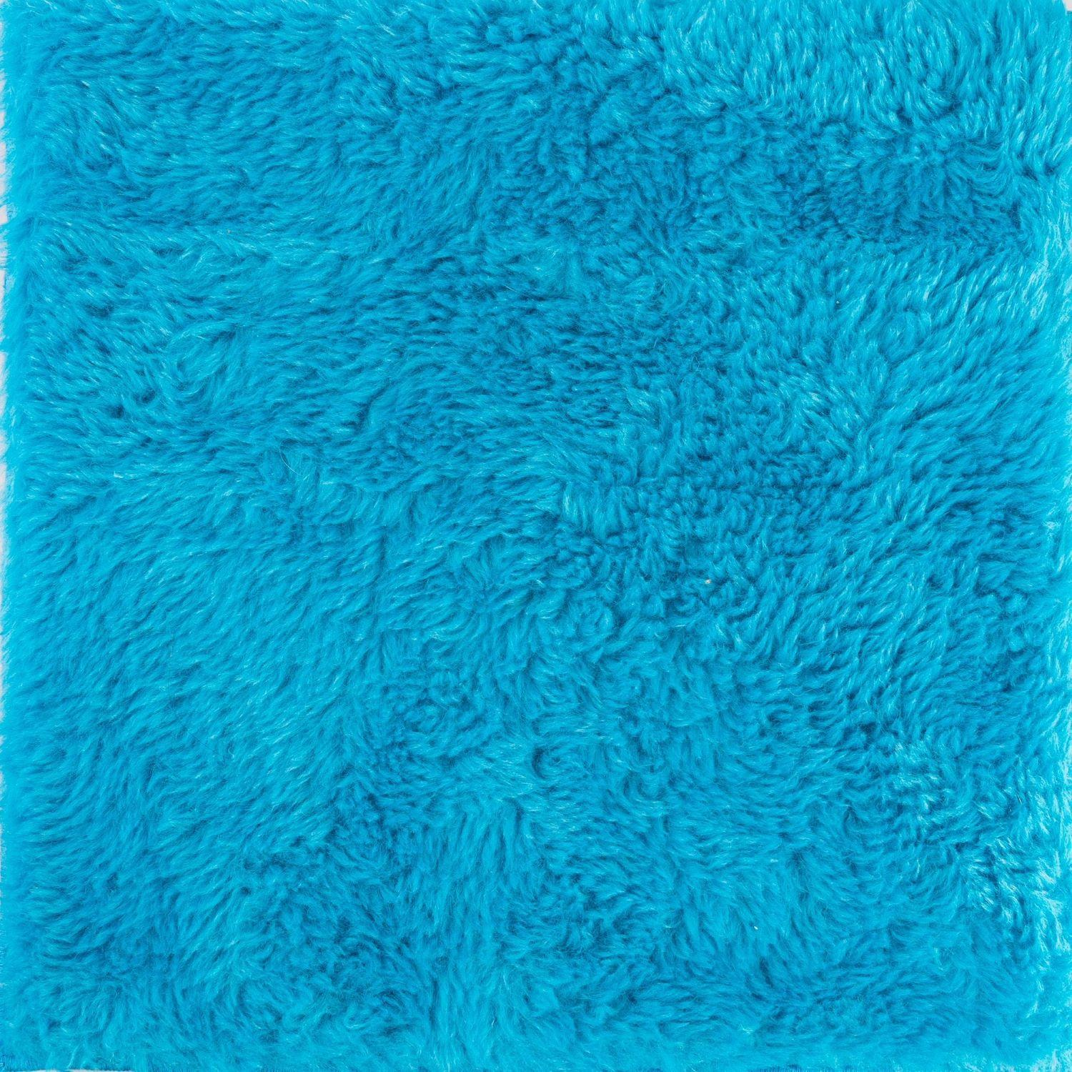 Nahaufnahme eines flauschigen, hellblauen Teppichs.