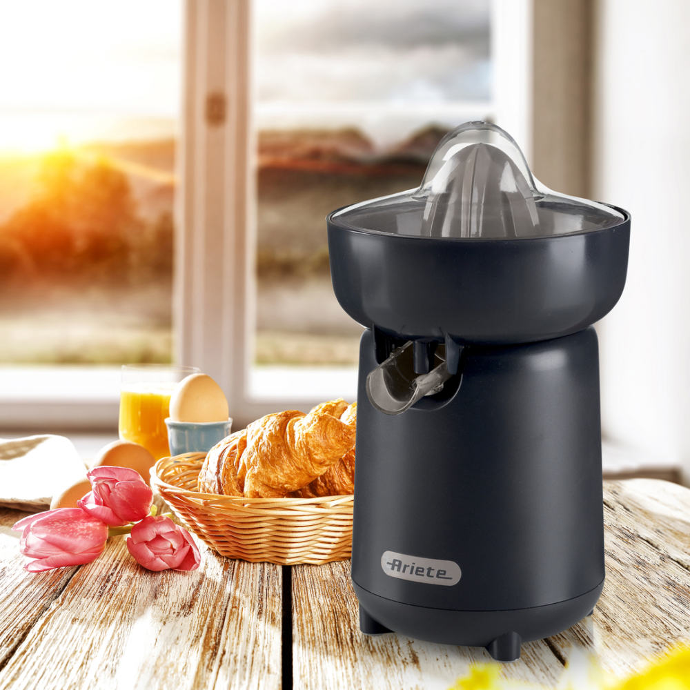 Gyümölcscentrifuga reggelizőasztal háttérrel, croissant-okkal, tojásokkal, narancslével és tulipánokkal. Napos.