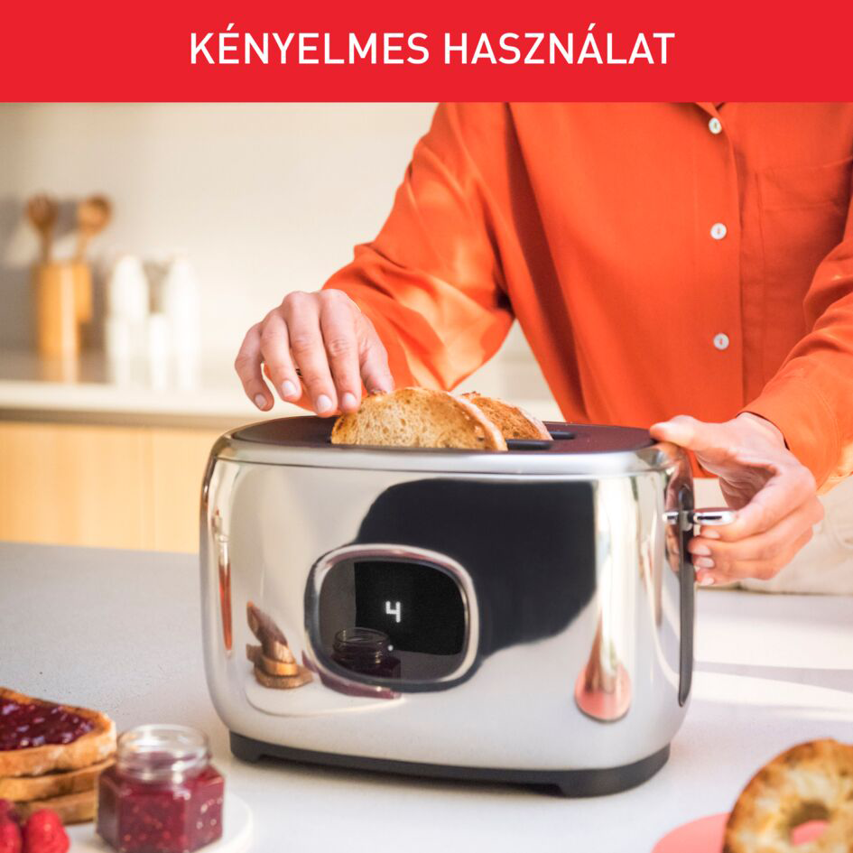 Egy személy kenyeret helyez egy króm kenyérpirítóba, lekvárral és pirítóssal a pulton.