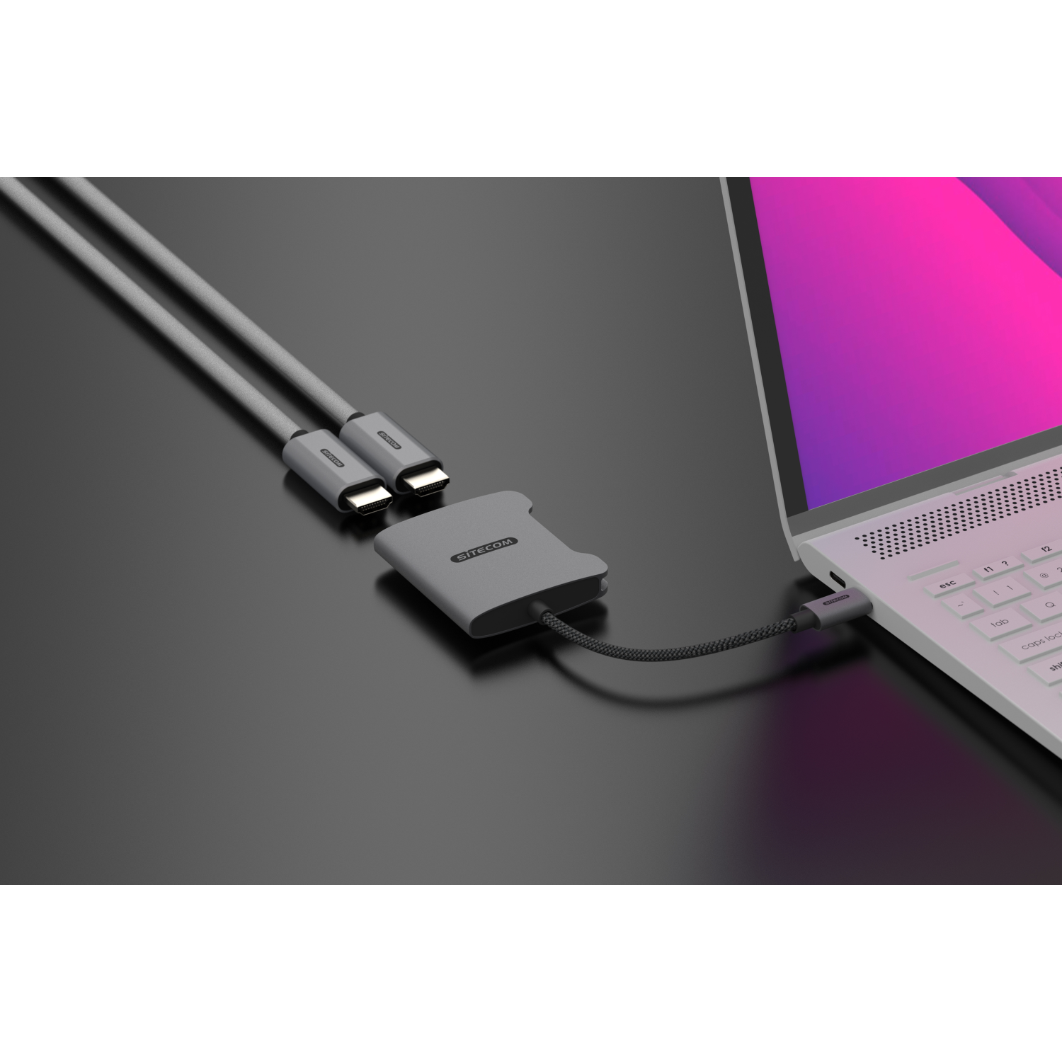 Gray adapter with two USB-C cables connected to a laptop on a black surface.