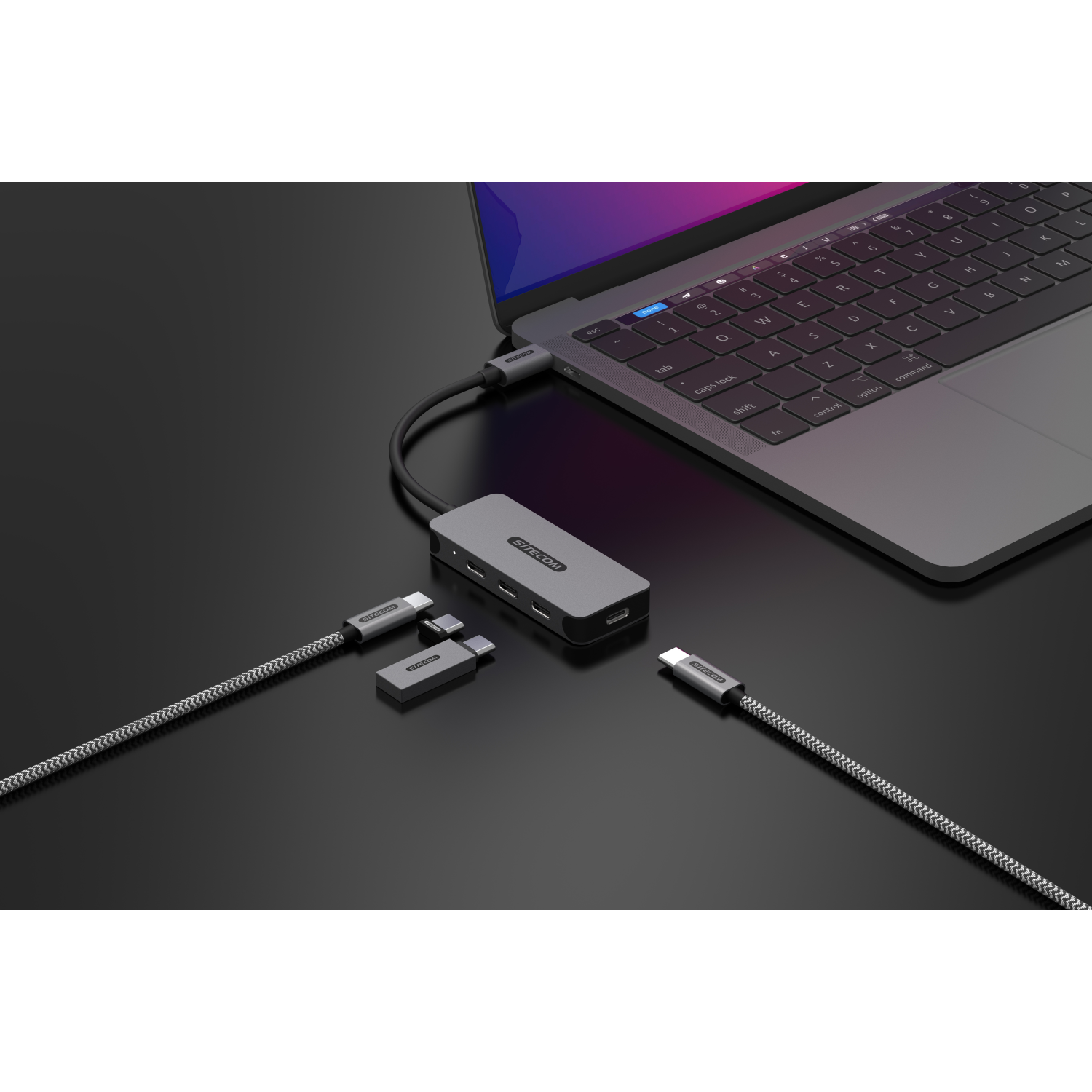 A laptop with a USB hub connected to it. USB cables are connected to the hub.