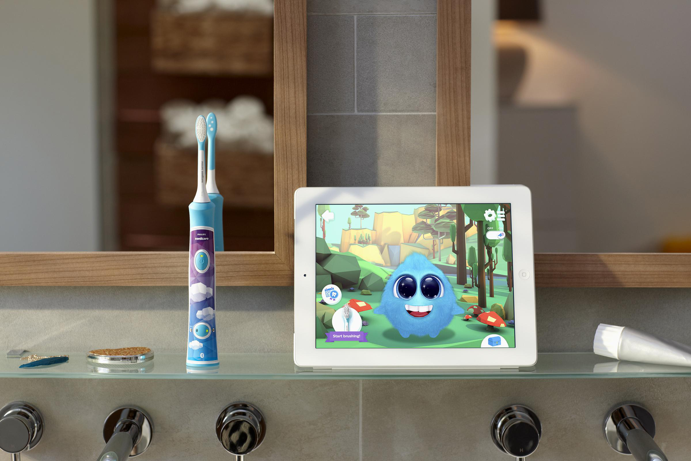 Eine Zahnbürste und ein Tablet, das eine Zeichentrickfigur zeigt, stehen auf einem Regal im Badezimmer mit Spiegel.