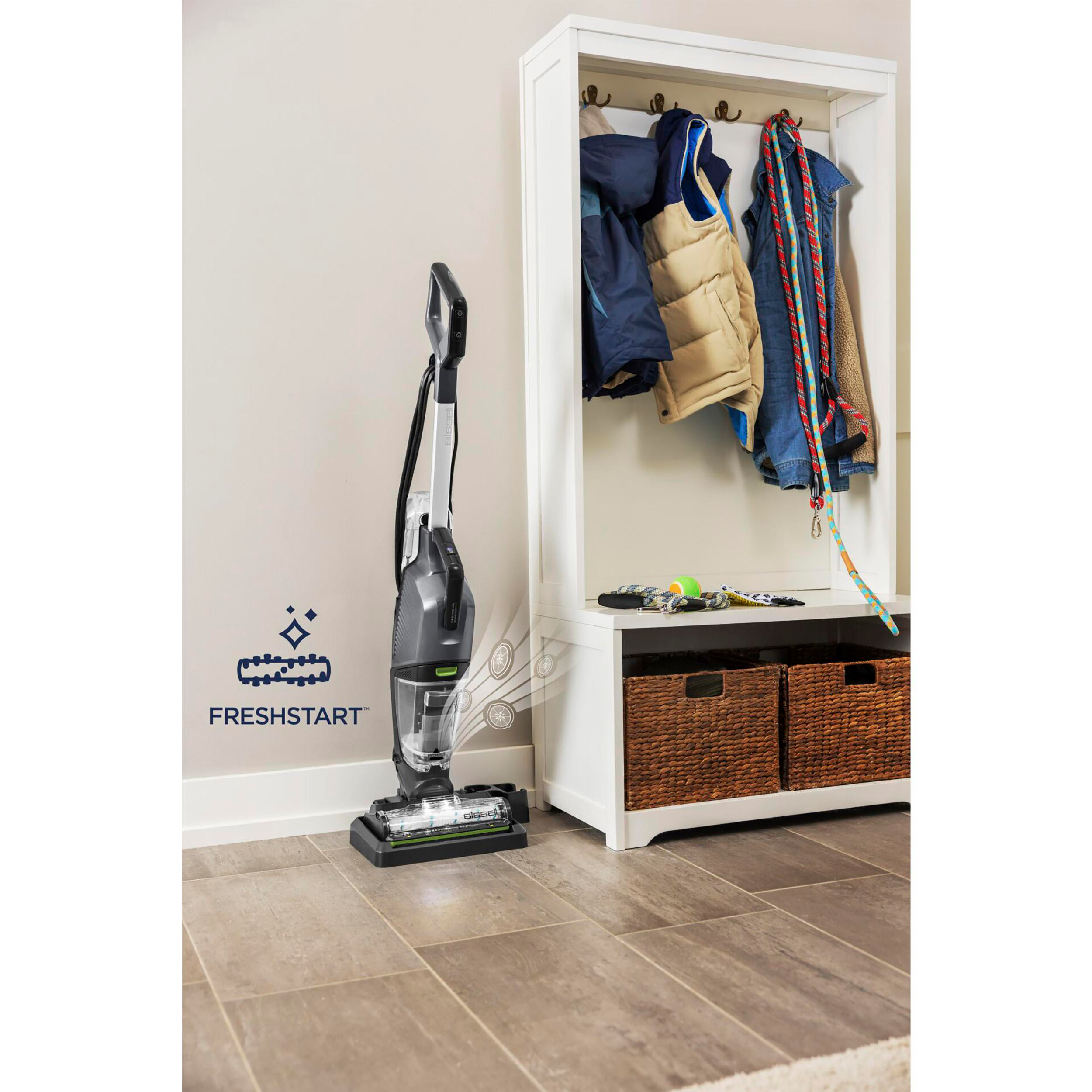 Ein Staubsauger neben einer Garderobe mit Mänteln und Körben.
