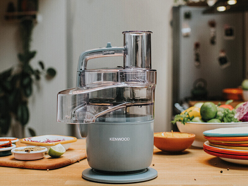 Robot kuchenny Kenwood stojący na drewnianej powierzchni kuchennej.
