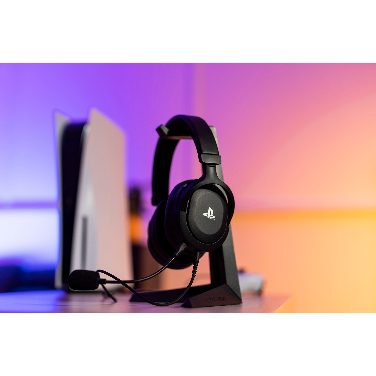 Black headphones with stand, a white game console, and a purple and blue background.