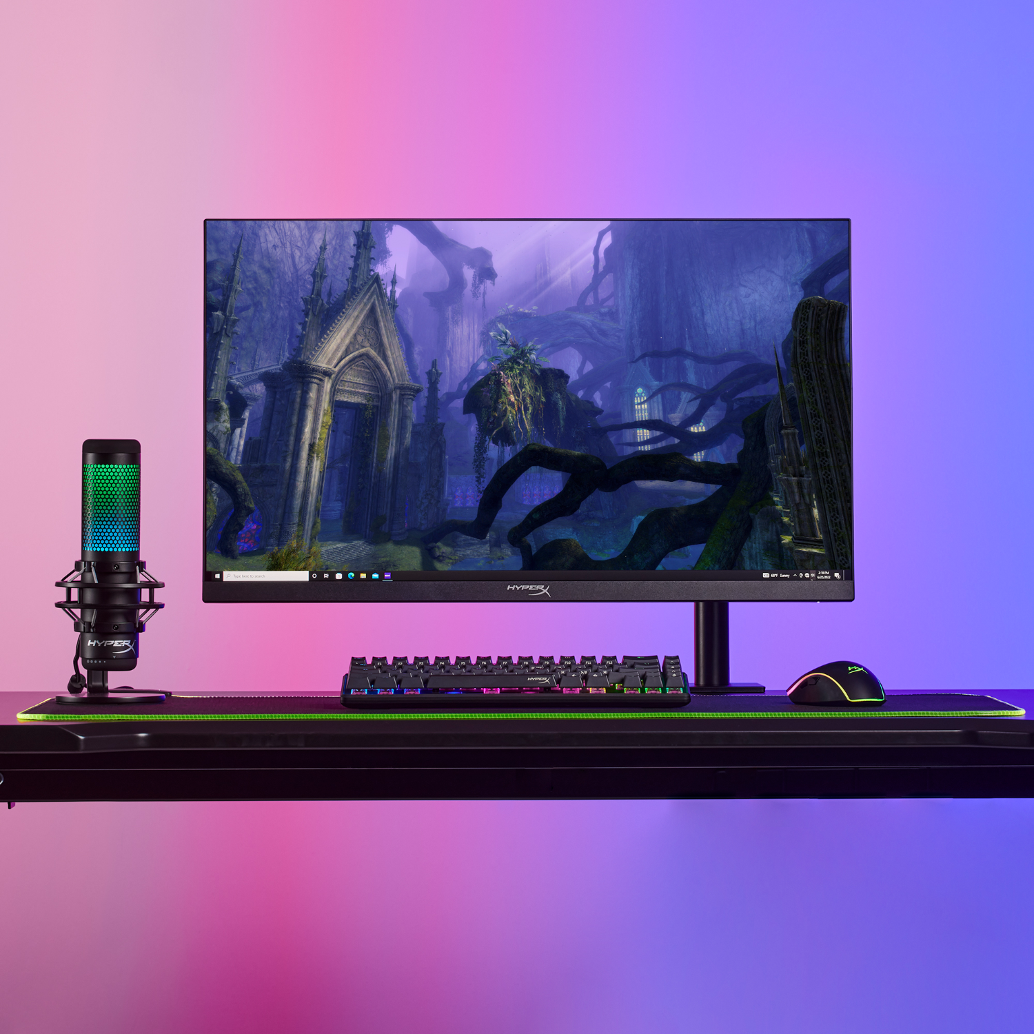Gaming setup met monitor, microfoon, toetsenbord en muis op een zwart bureau.
