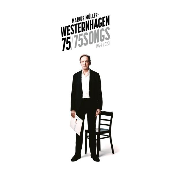 Mann im Anzug hält ein Albumcover vor einem Stuhl. Weißer Hintergrund.