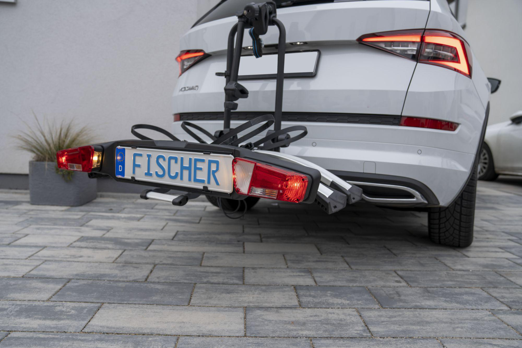Ein weißes Auto mit Fahrradträger. Das Nummernschild lautet FISCHER.