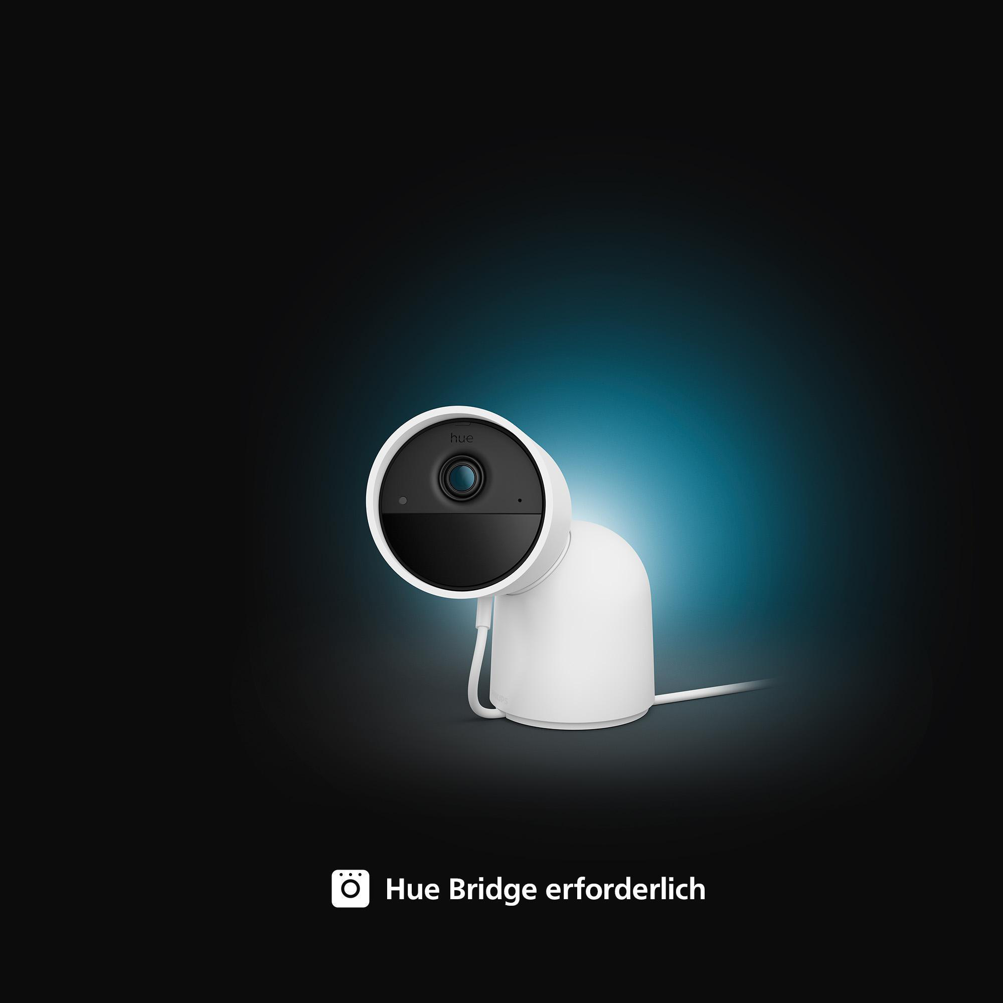 Eine weiße Überwachungskamera mit schwarzer Front auf schwarz-blauem Hintergrund. Der Text 'Hue Bridge erforderlich' erscheint.