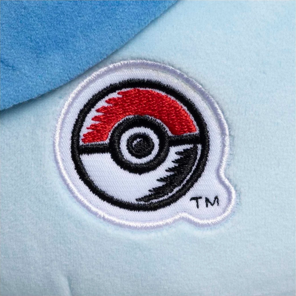 Nahaufnahme eines Pokémon-Stickpatches auf hellblauem Stoff, mit Pokéball-Design.