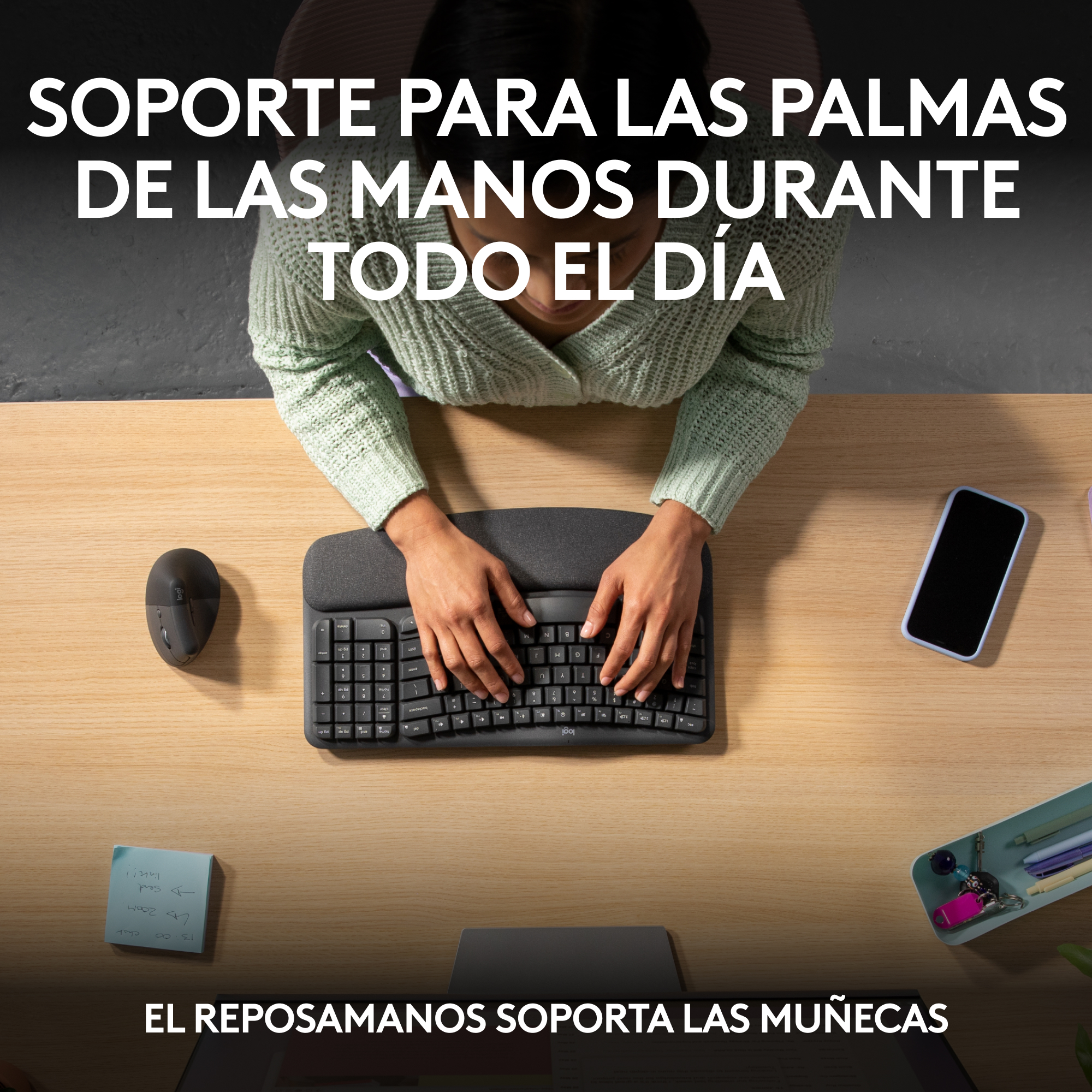 Manos tecleando en un teclado ergonómico, con ratón y teléfono.