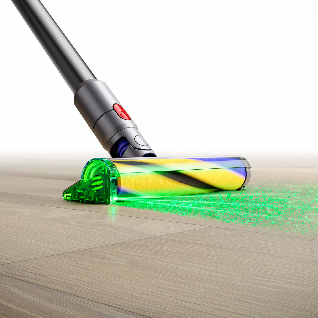 Zbliżenie głowicy odkurzacza Dyson na podłodze z zielonym światłem podkreślającym zanieczyszczenia.