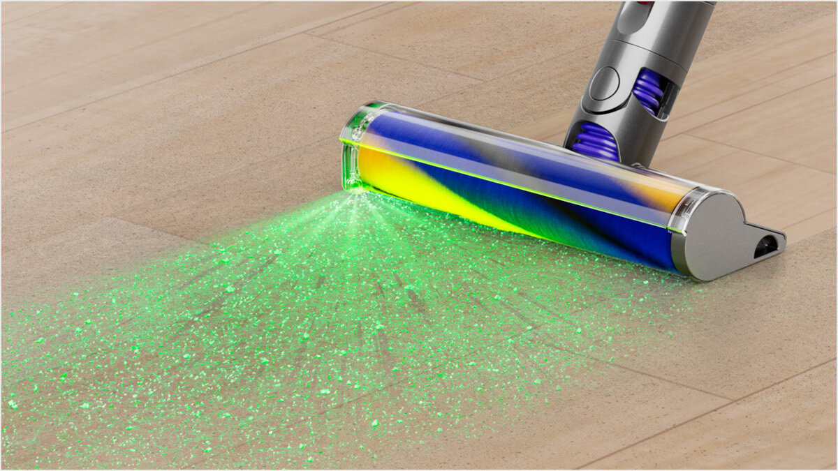 Głowica odkurzacza na drewnianej podłodze, pokazująca zielone światło lasera oświetlające cząsteczki kurzu.