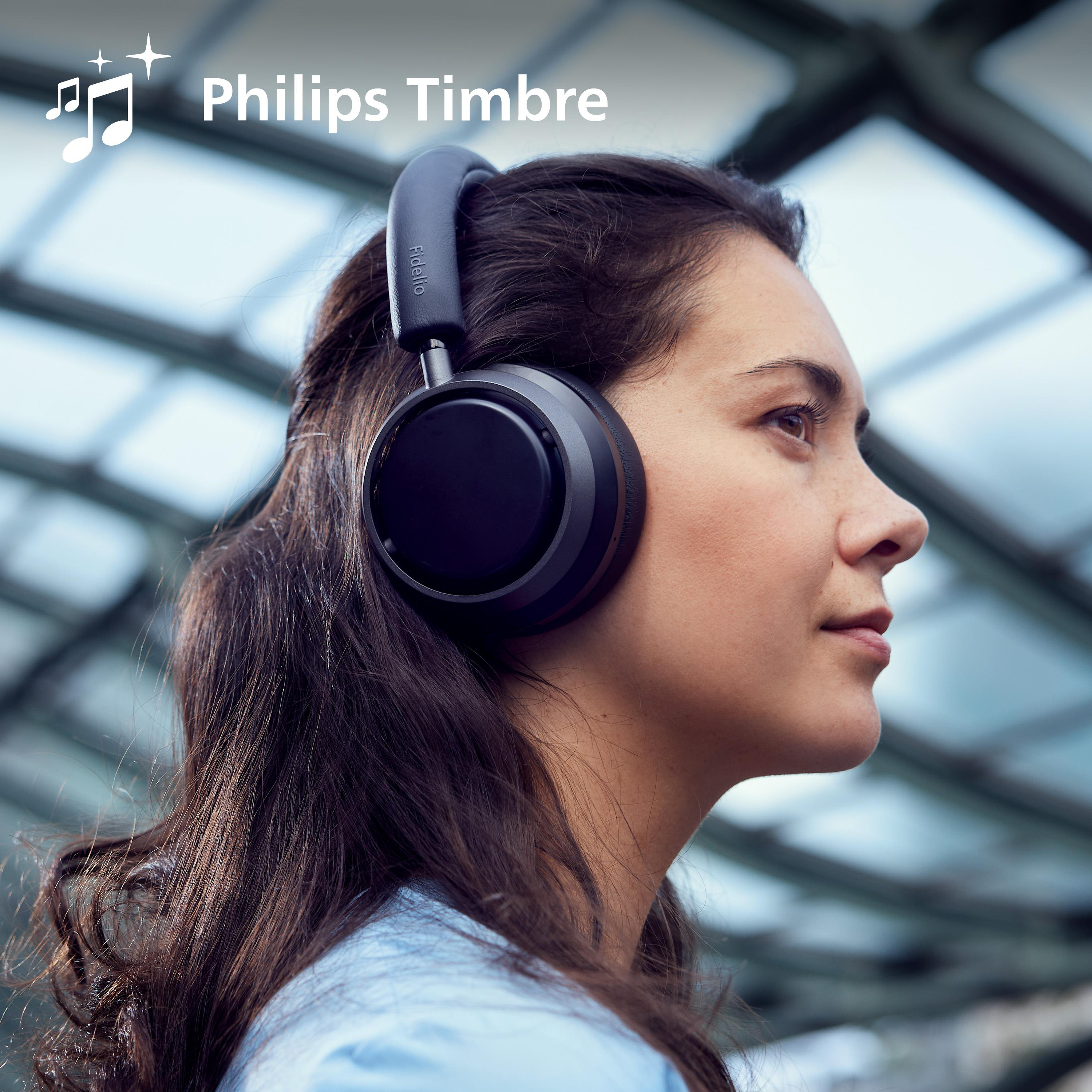 Frau mit schwarzen Kopfhörern. Verschwommener Hintergrund. Kopfhörermarke ist Philips Timbre.
