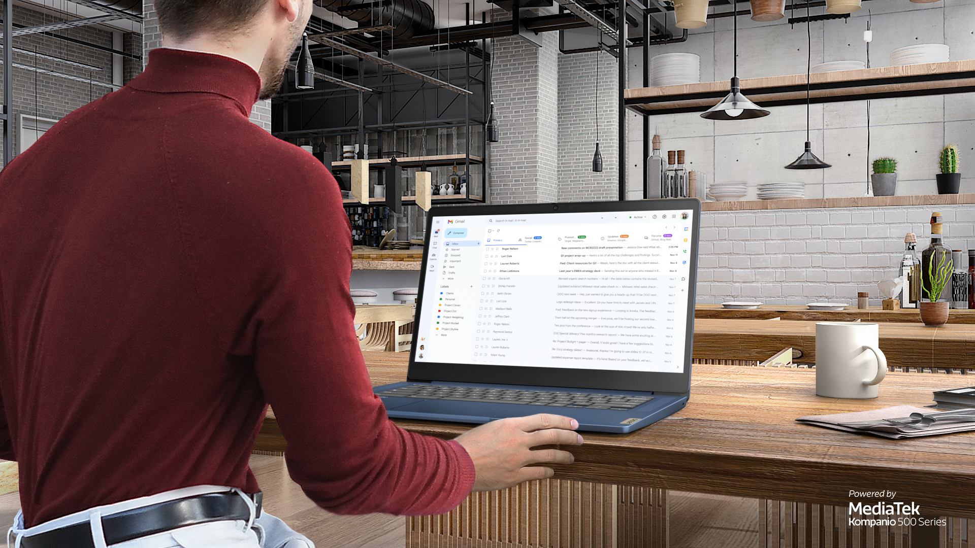 Mann benutzt blauen Laptop am Holztisch im Café.