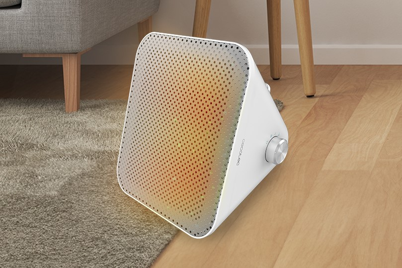 Un calefactor triangular blanco sobre un suelo de madera, con una perilla de control.