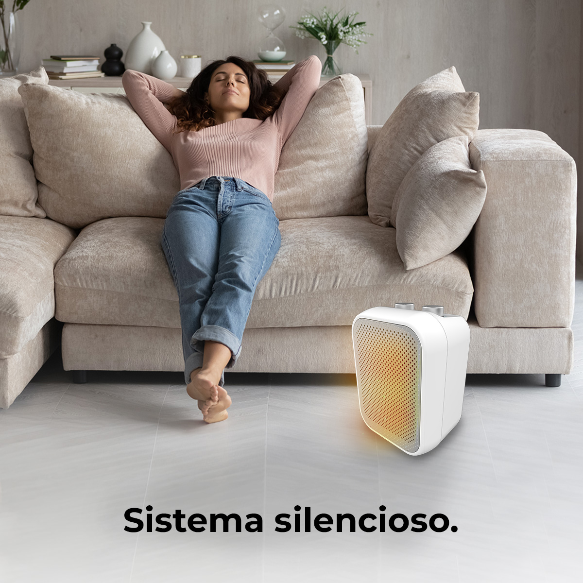 Mujer relajándose en un sofá beige, con un calefactor blanco cerca.