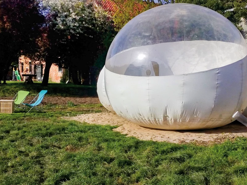 Grande tente bulle sur l'herbe. Deux chaises sont installées à l'extérieur.