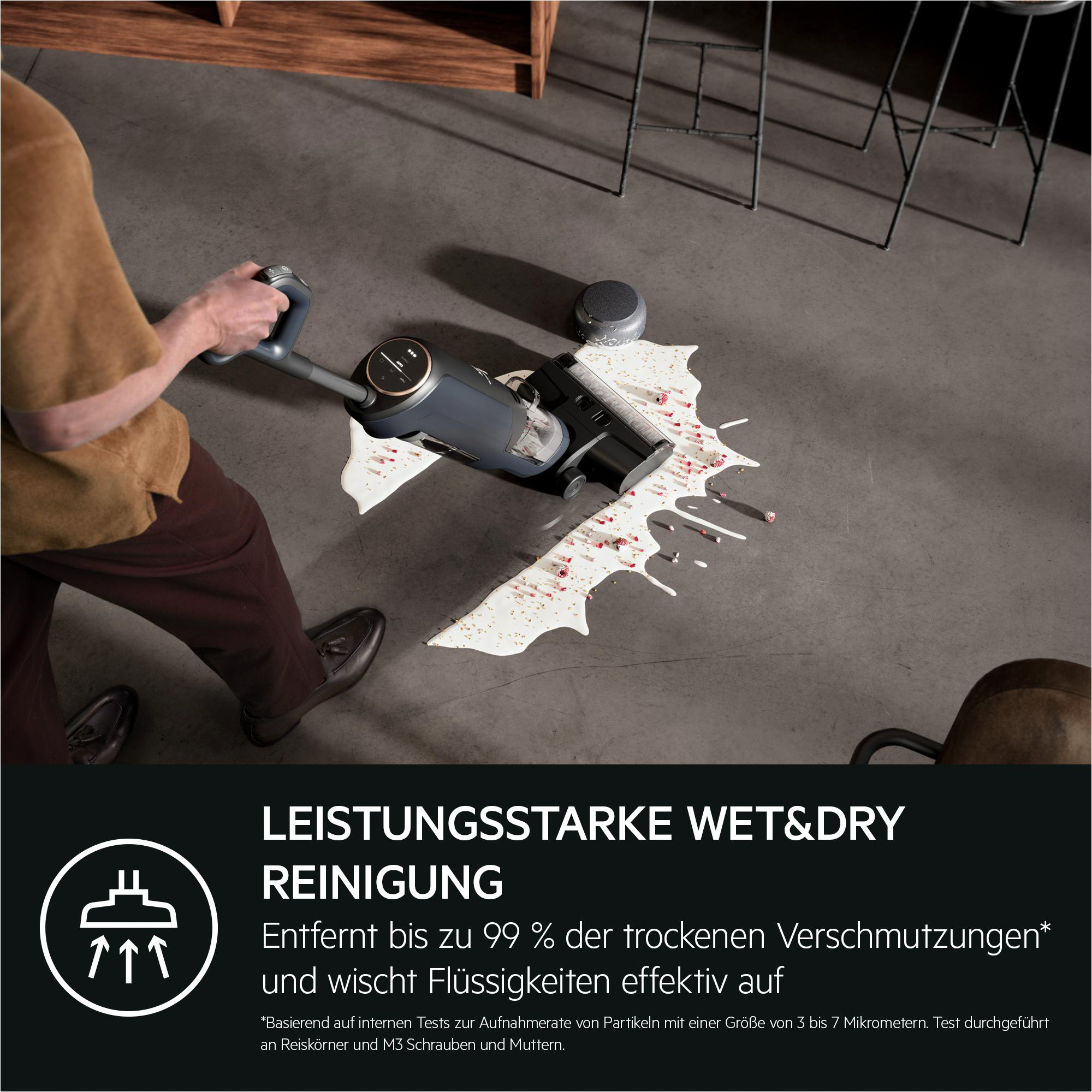 Person reinigt weißen Flüssigkeitsfleck mit einem Staubsauger. Text: Leistungsstarke Nass- & Trockenreinigung.
