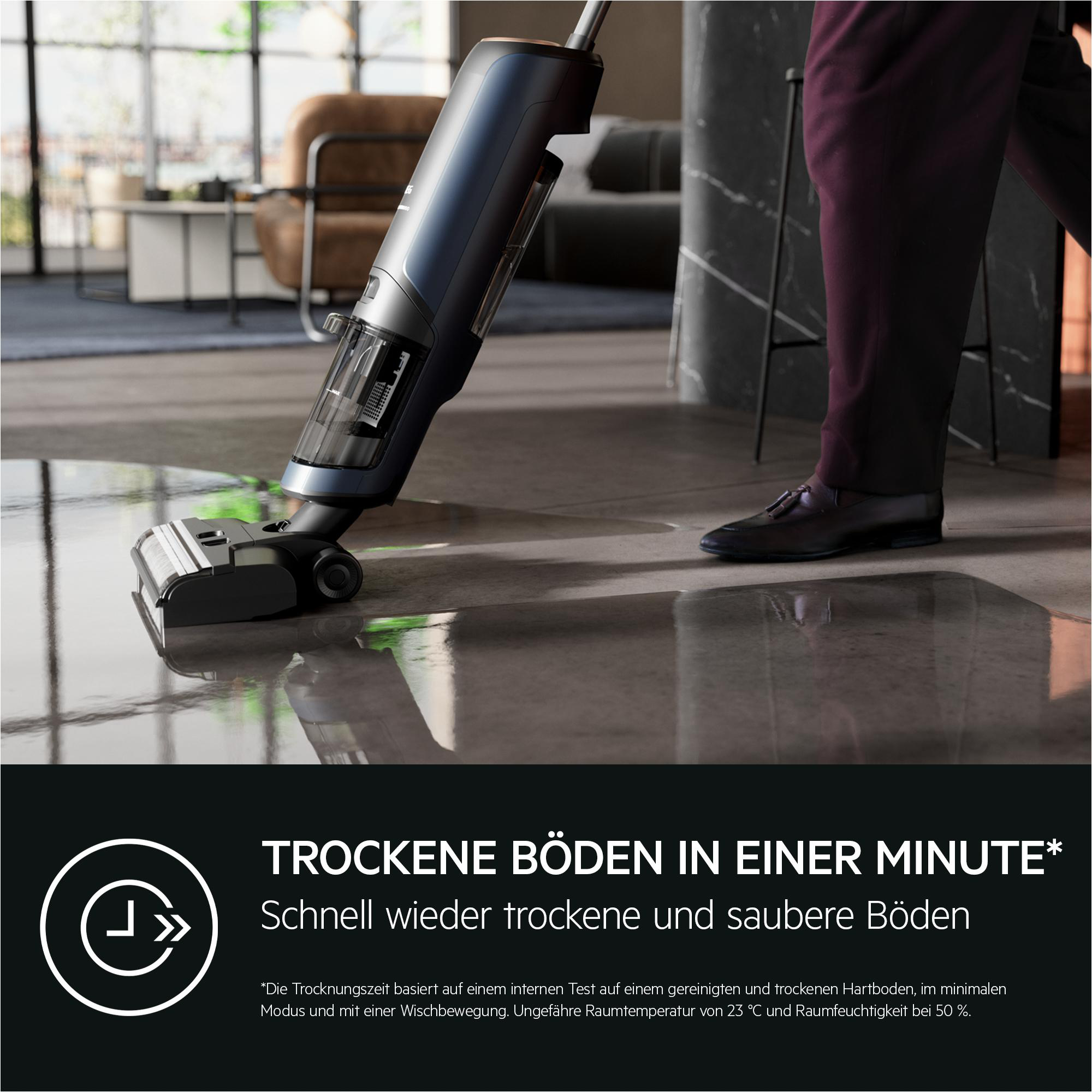 Person saugt einen nassen Boden mit einem blau-schwarzen Staubsauger. Text: Trockene Böden in einer Minute.